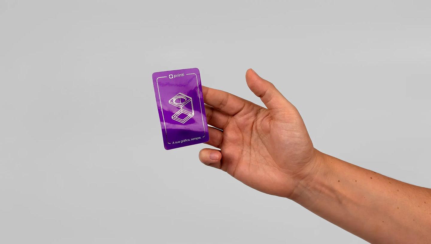 Adesivo personalizado com acabamento em verniz localizado sendo segurado na mão, destacando brilho e qualidade de impressão.
