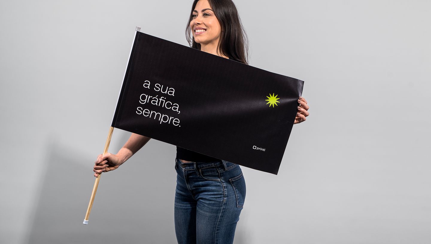 Mulher branca sorrindo enquanto segura bandeira personalizada com fundo branco e liso