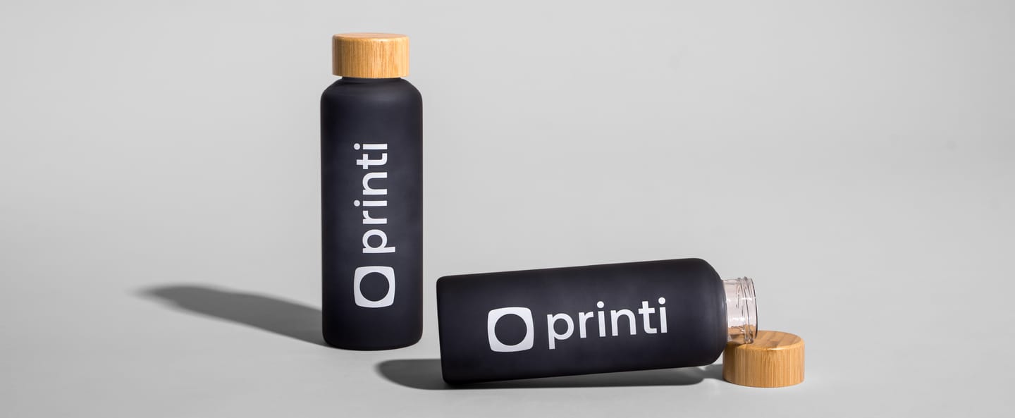 Squeezes personalizados pretos com tampa de madeira e logotipo Printi em destaque.