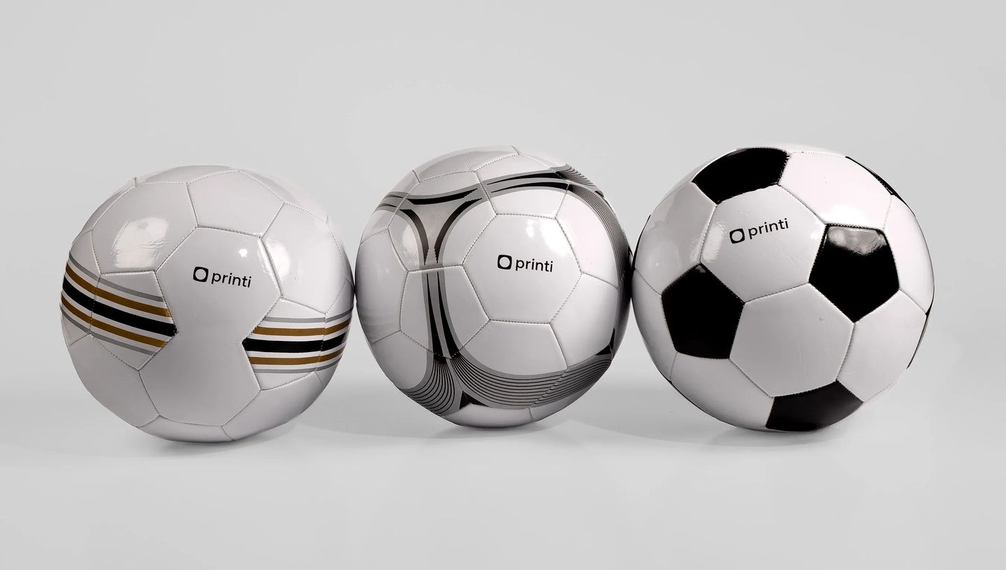 Trio de bolas de futebol personalizadas com diferentes grafismos e logotipo centralizado.