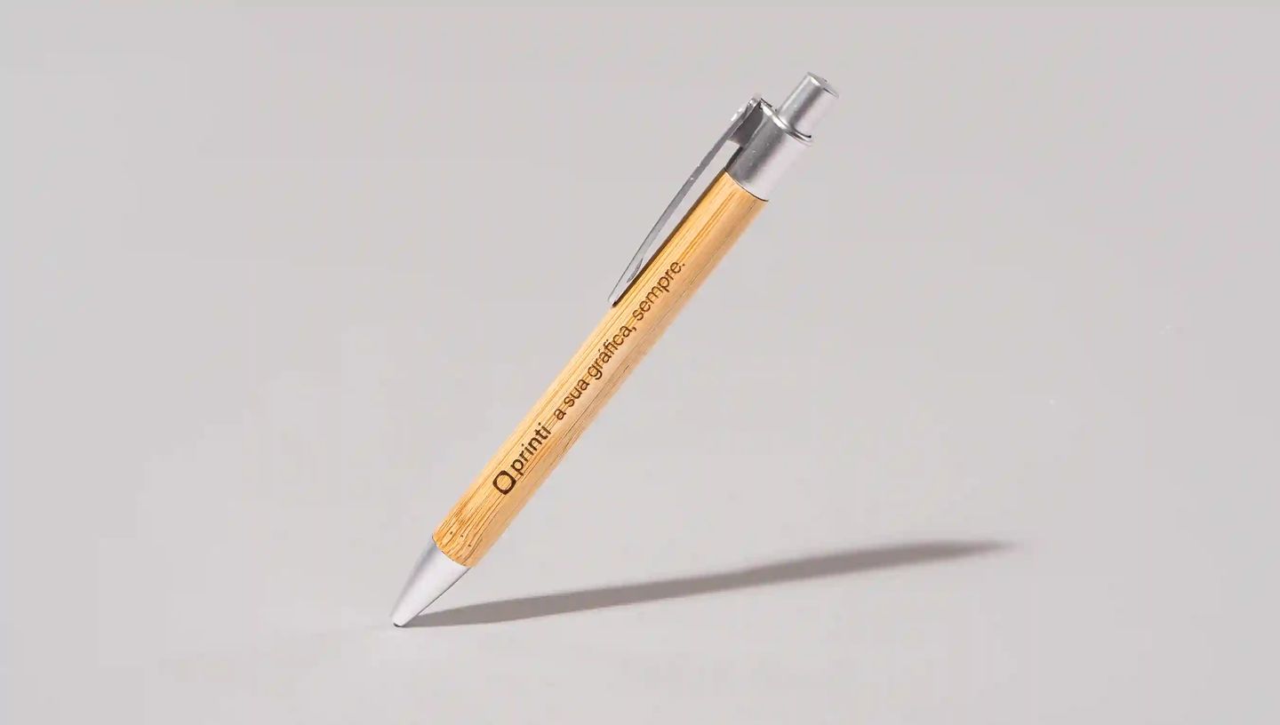 Caneta ecológica personalizada com corpo em bambu natural e detalhes metálicos prateados, com gravação da marca Printi ao longo do corpo, exibida inclinada sobre fundo neutro, representando um brinde corporativo sustentável ideal para ações promocionais, 