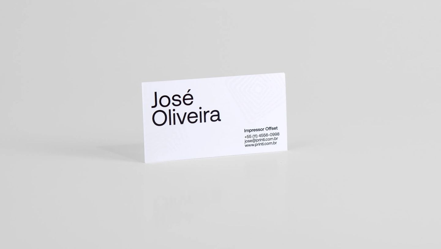 Cartão de visita profissional em papel branco com design minimalista em preto, exibindo o nome “José Oliveira” e informações de contato, apresentado em estúdio sobre fundo neutro para destacar o layout limpo e tipografia moderna do material impresso.