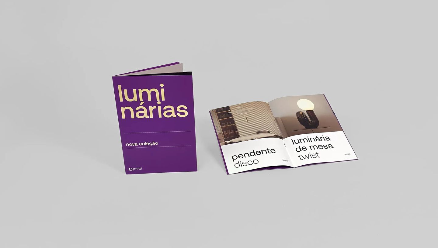 Catálogo personalizado roxo aberto exibindo fotos de luminárias e acabamento em hot stamping dourado.