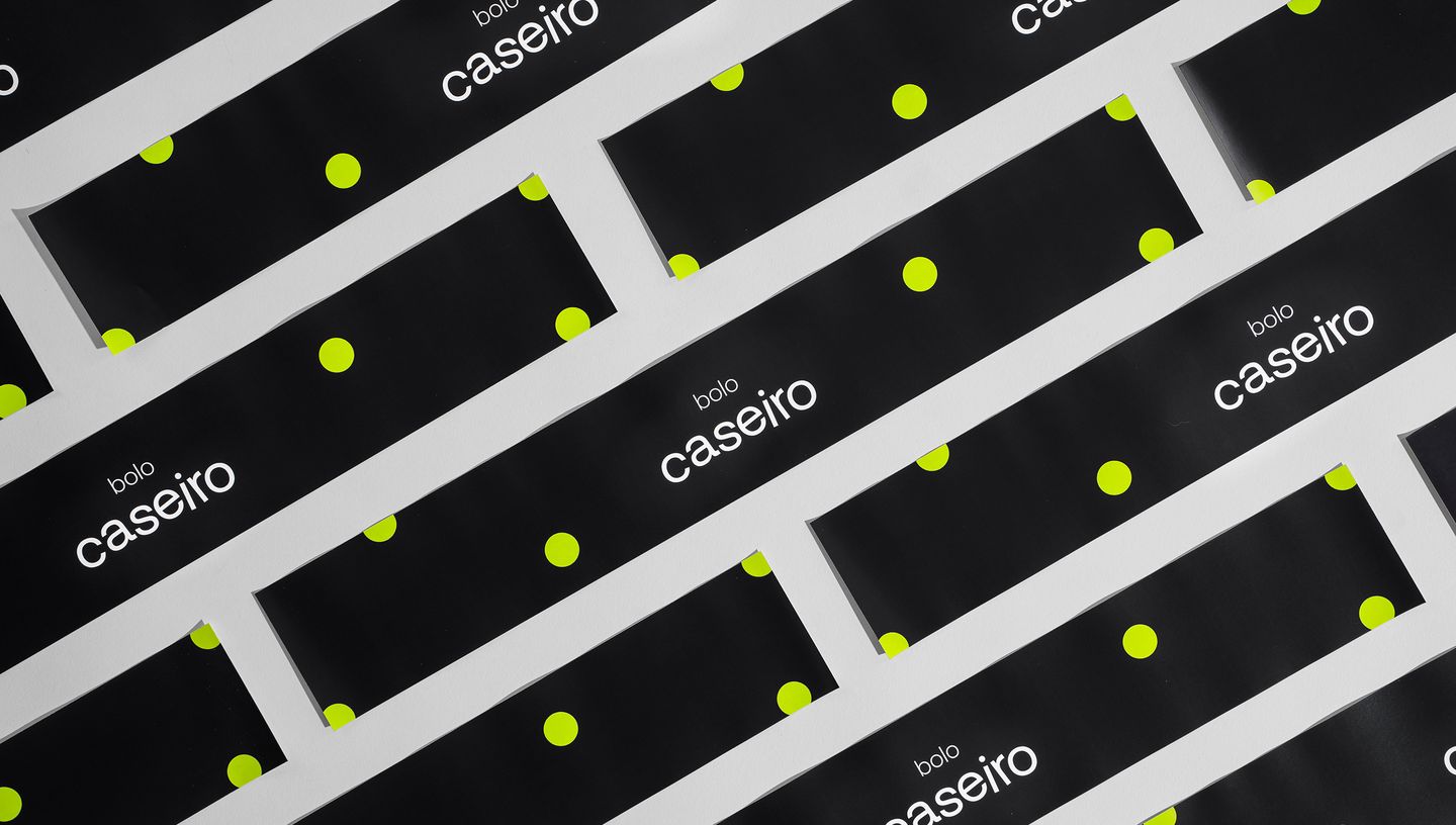 Diversas cintas para bolo com design moderno e estampa de bolinhas verdes sobre fundo preto, organizadas em folhas para aplicação em embalagens de bolos caseiros.