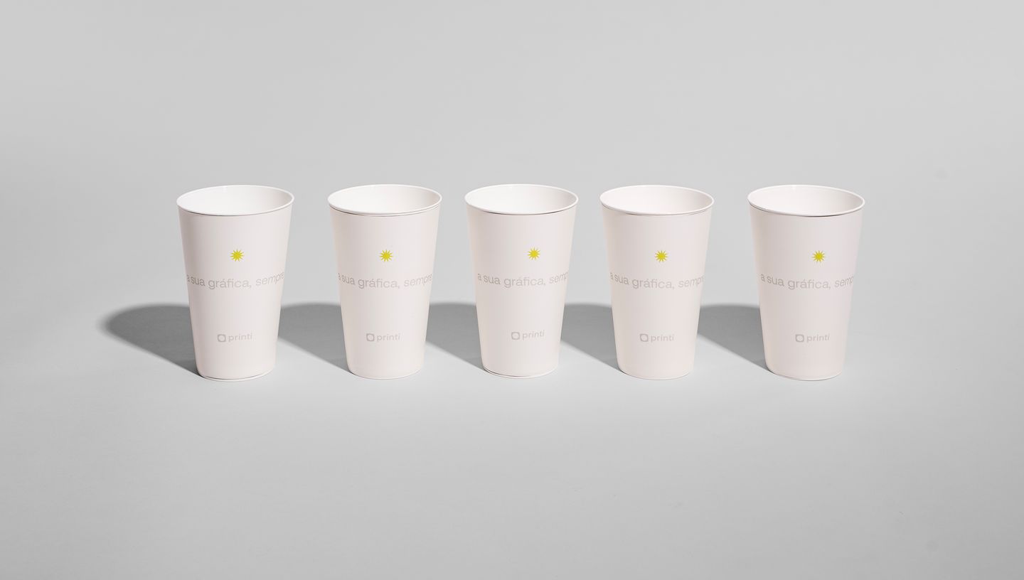 Cinco unidades de Copo in Mold personalizadas com logo da Printi, alinhadas sobre fundo cinza neutro.