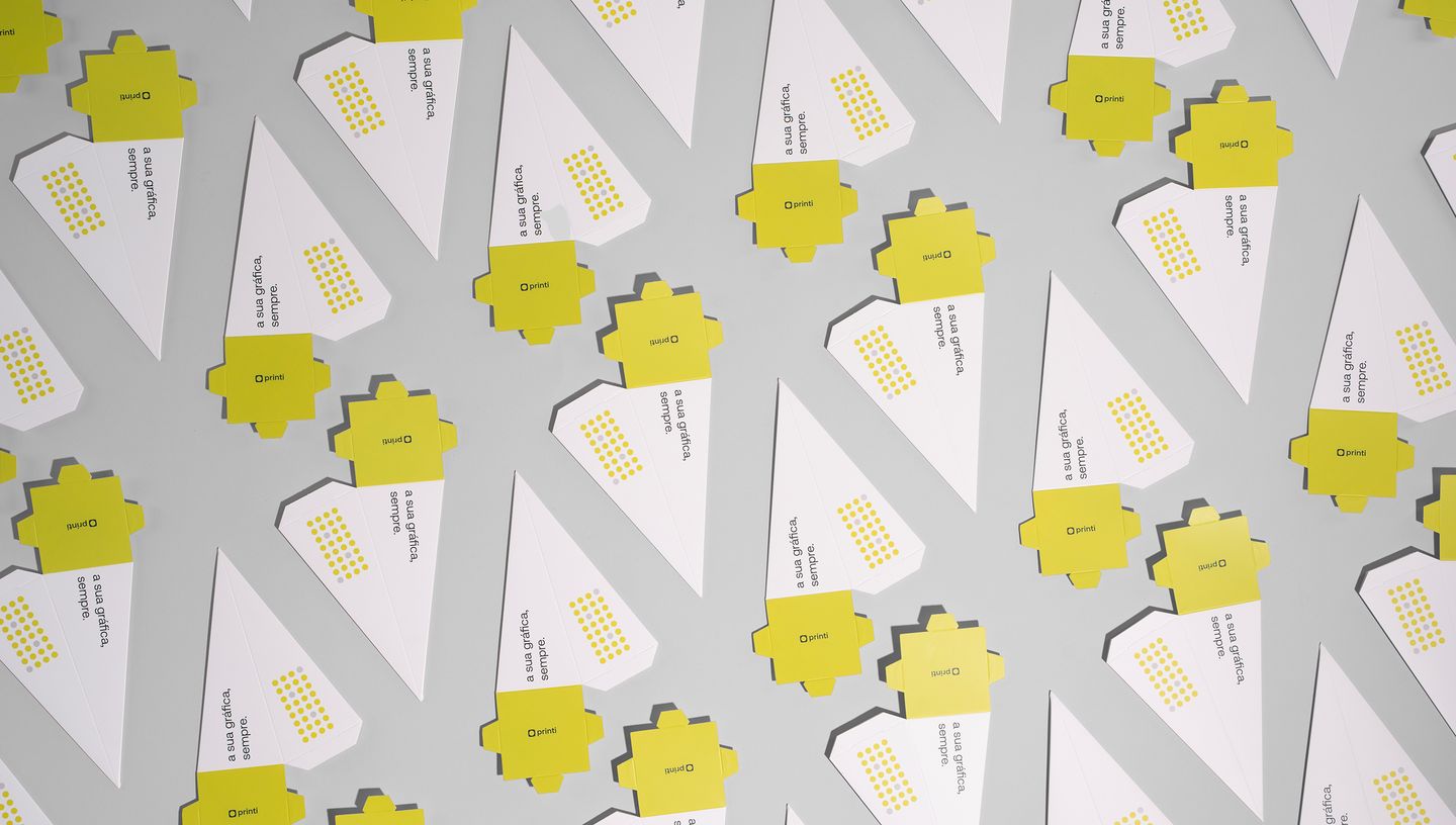 Embalagens pirâmides desmontadas, nas cores branco e amarelo.