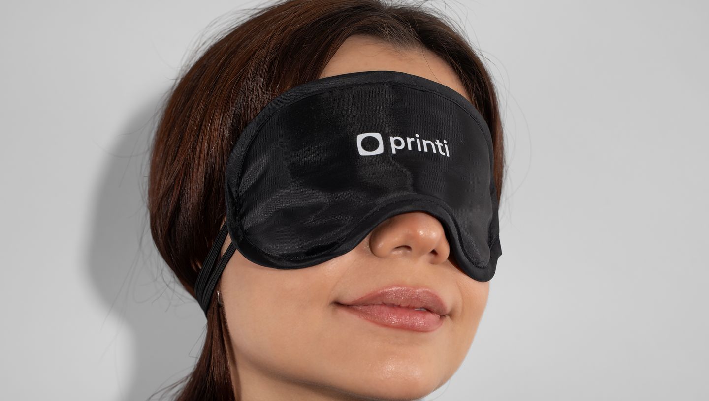 Mulher com máscara para dormir na cor preta com logo da Printi.