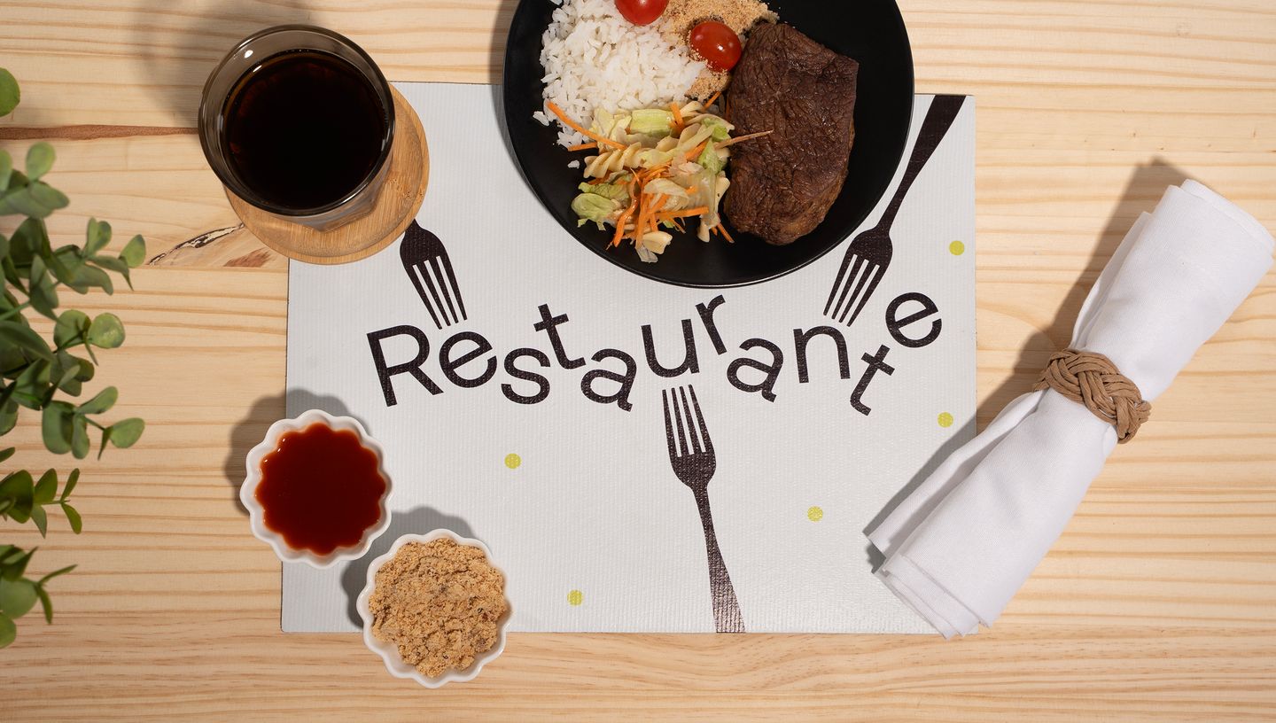 Jogo americano de plástico com comida em mesa de madeira
