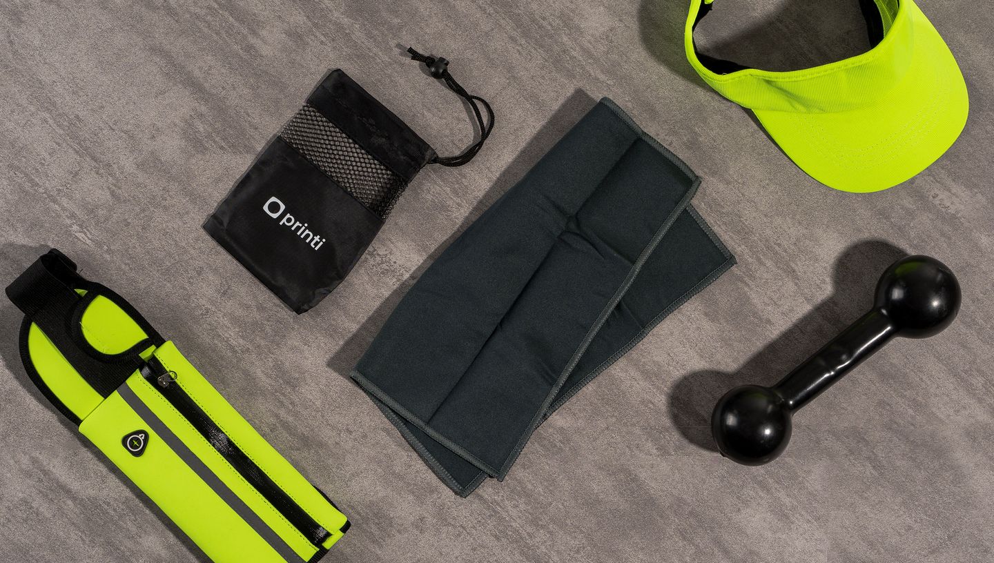 Toalha esportiva de microfibra ao lado da embalagem e material de treino esportivo.