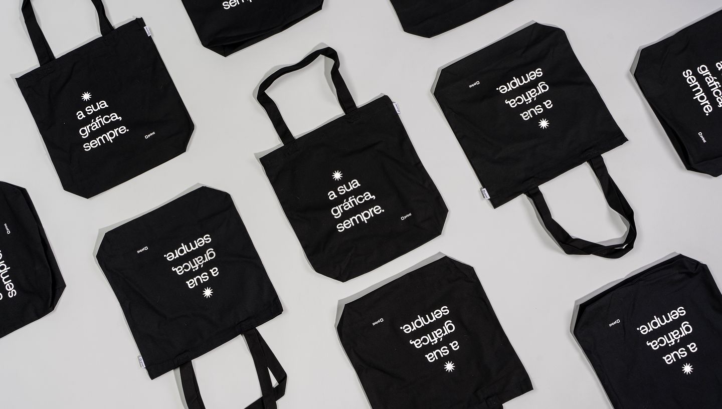 Com certeza! As sacolas de algodão reciclado (ou ecobags) são muito populares. Aqui estão as opções de alt text para SEO para as duas imagens.  Imagem 1 (Com a modelo) Opção 1 (Curta e Direta): Mulher segurando uma ecobag preta de algodão reciclado com a 