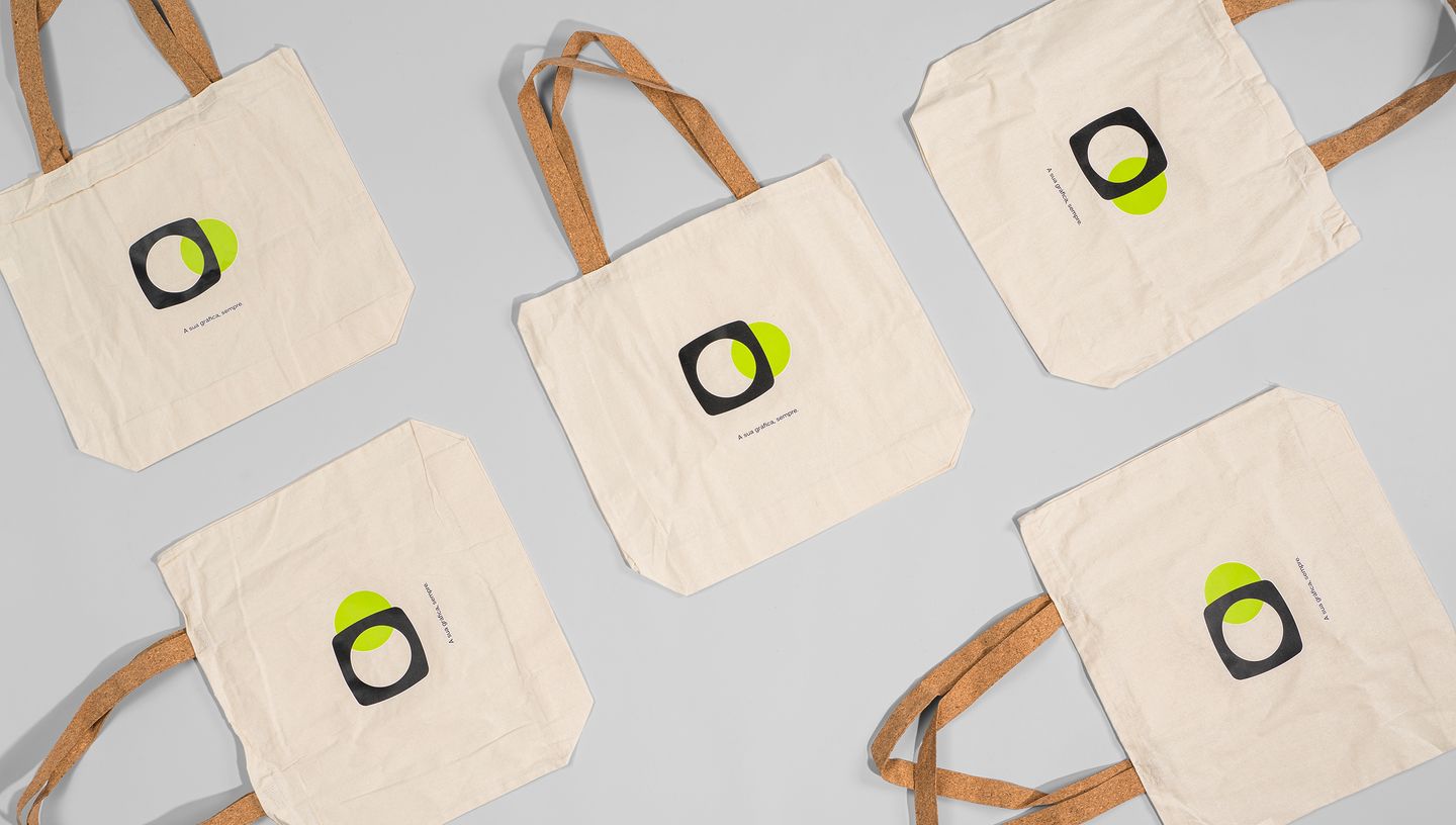 Cinco ecobags com a logomarca da Printi em fundo cinza