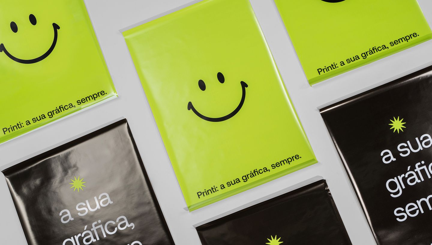 Lona backlight personalizada na cor verde com smile e slogan da Printi e outra na cor preta com o slogan