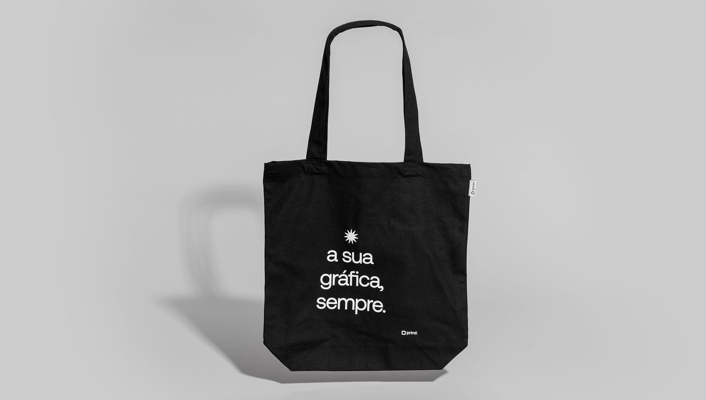 Com certeza! As sacolas de algodão reciclado (ou ecobags) são muito populares. Aqui estão as opções de alt text para SEO para as duas imagens.  Imagem 1 (Com a modelo) Opção 1 (Curta e Direta): Mulher segurando uma ecobag preta de algodão reciclado com a 