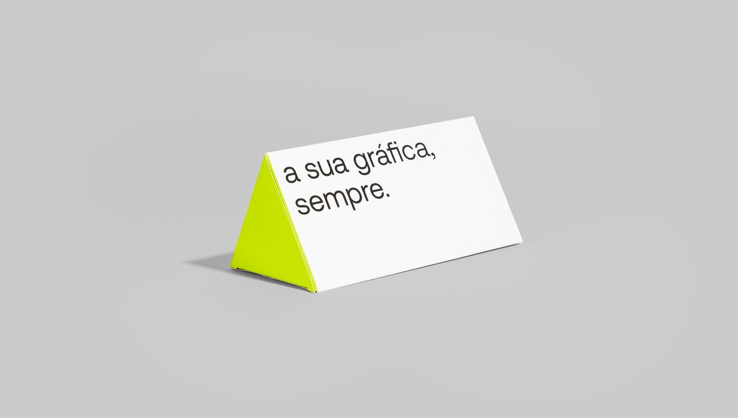 Embalagem triangular nas cores branco e verde, com slogam da Printi.