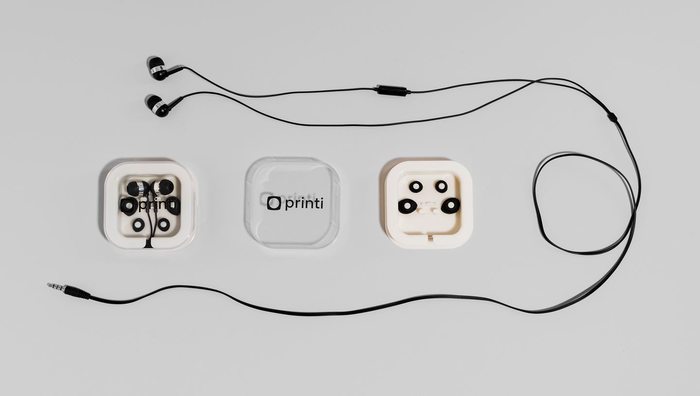 Fone de ouvido com microfone personalizado com logo da Printi na capa, com todos os acessórios ao redor.
