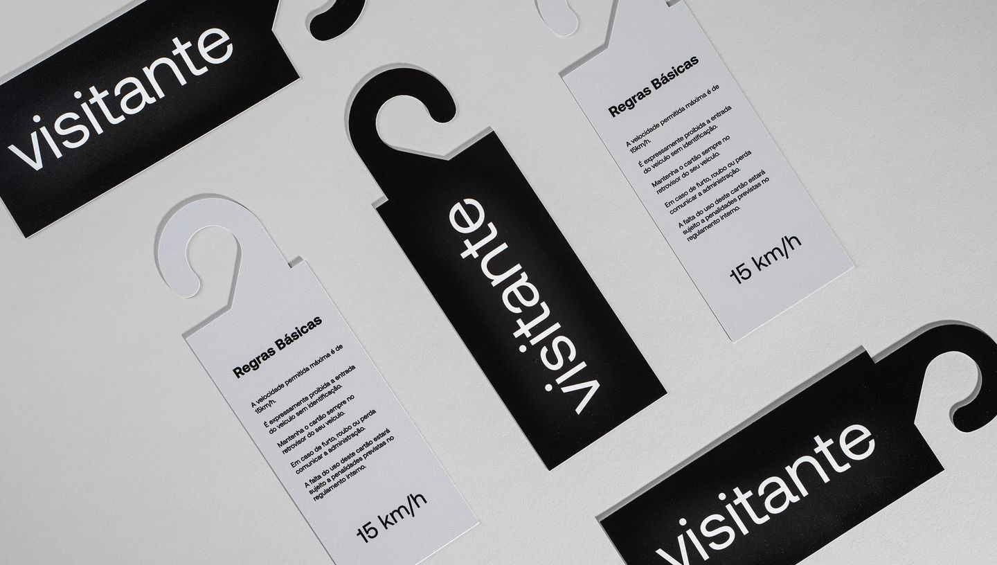 Vários modelos de Display Retrovisor com design preto e branco e informações para visitantes, dispostos em padrão sobre fundo cinza claro.