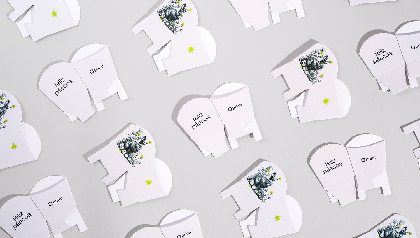 Embalagens cachepot desmontadas com arte de coelho e mensagem "Feliz Páscoa"