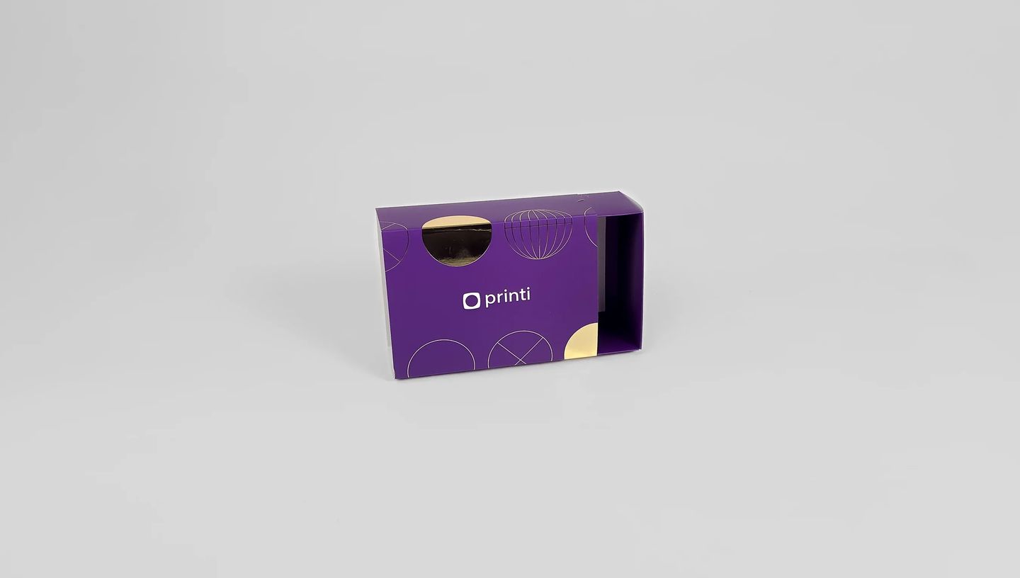 Embalagem gaveta personalizada roxa com detalhes em hot stamping dourado e logotipo Printi centralizado.