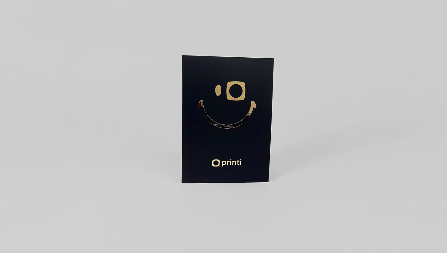 Flyer personalizado azul-marinho com acabamento dourado metalizado e logo impresso, exibido em mockup minimalista.