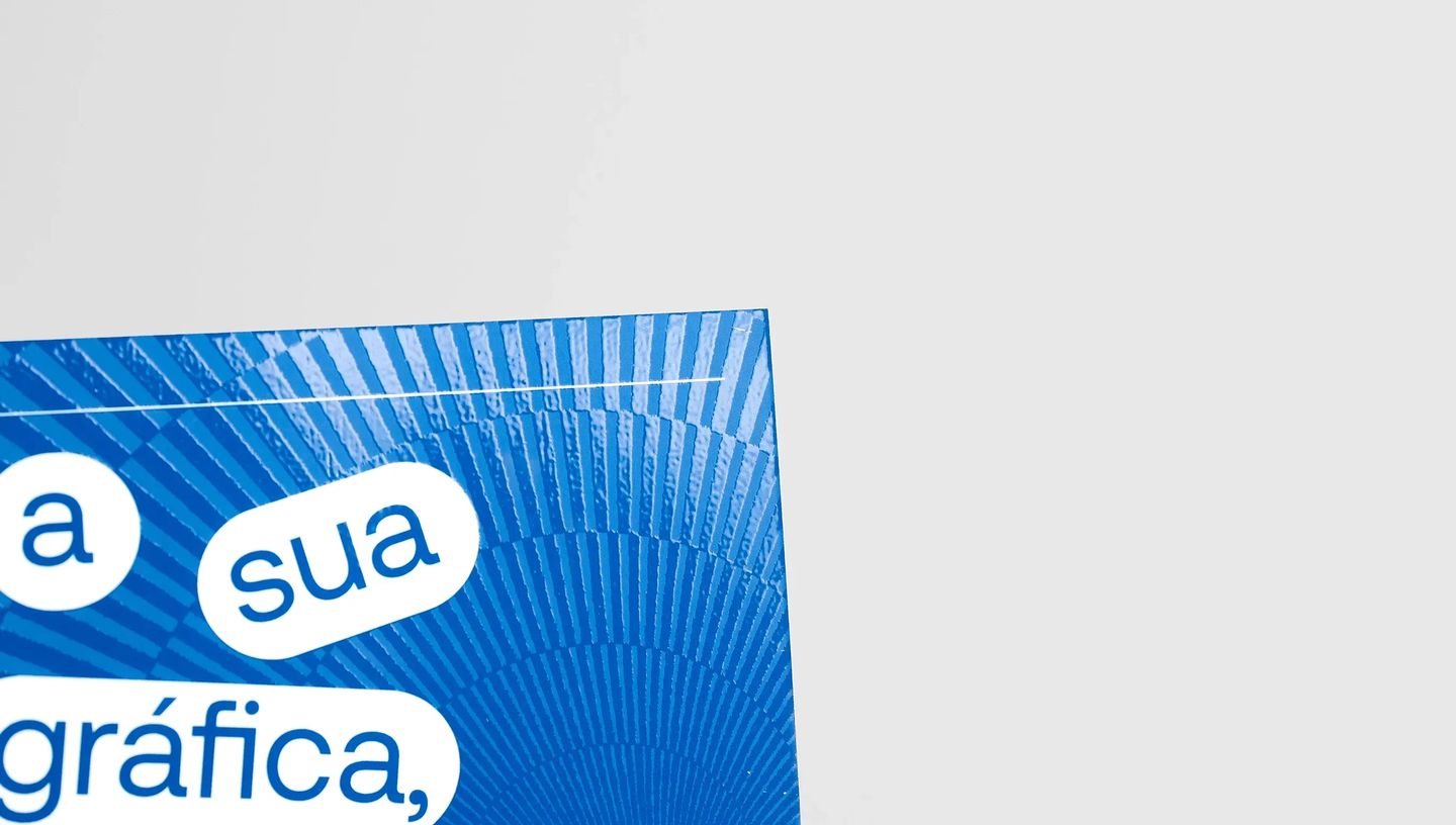 Detalhe de flyer azul personalizado destacando acabamento em verniz localizado e frase institucional.