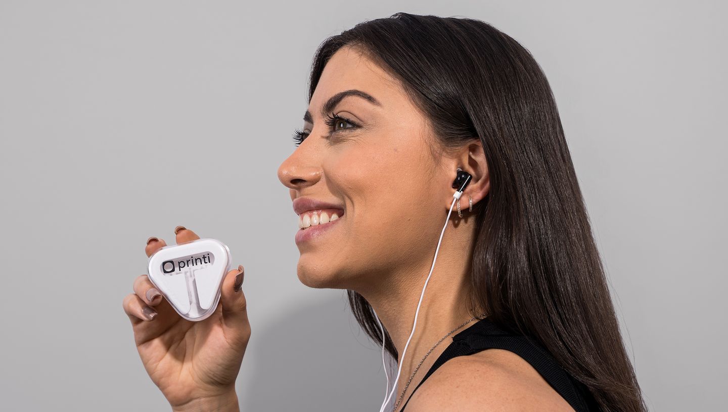 Mulher sorrindo enquanto utiliza Fone de Ouvido Intra Auricular da Printi, segurando o estojo personalizado com o logotipo