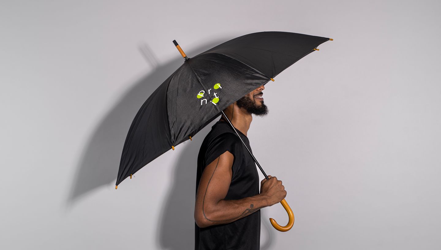 Homem negro de barba usando uma blusa de manga preta, segurando guarda-chuva preto com cabo de madeira e estampa personalizada da Printi