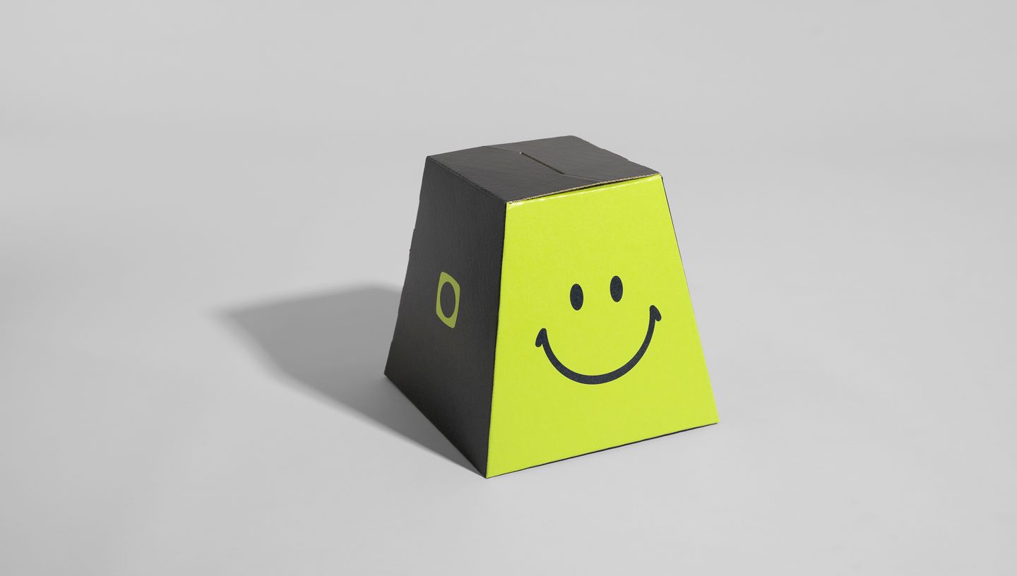 Urna de papelão montada da Printi com estampa de carinha sorridente e acabamento em preto e verde