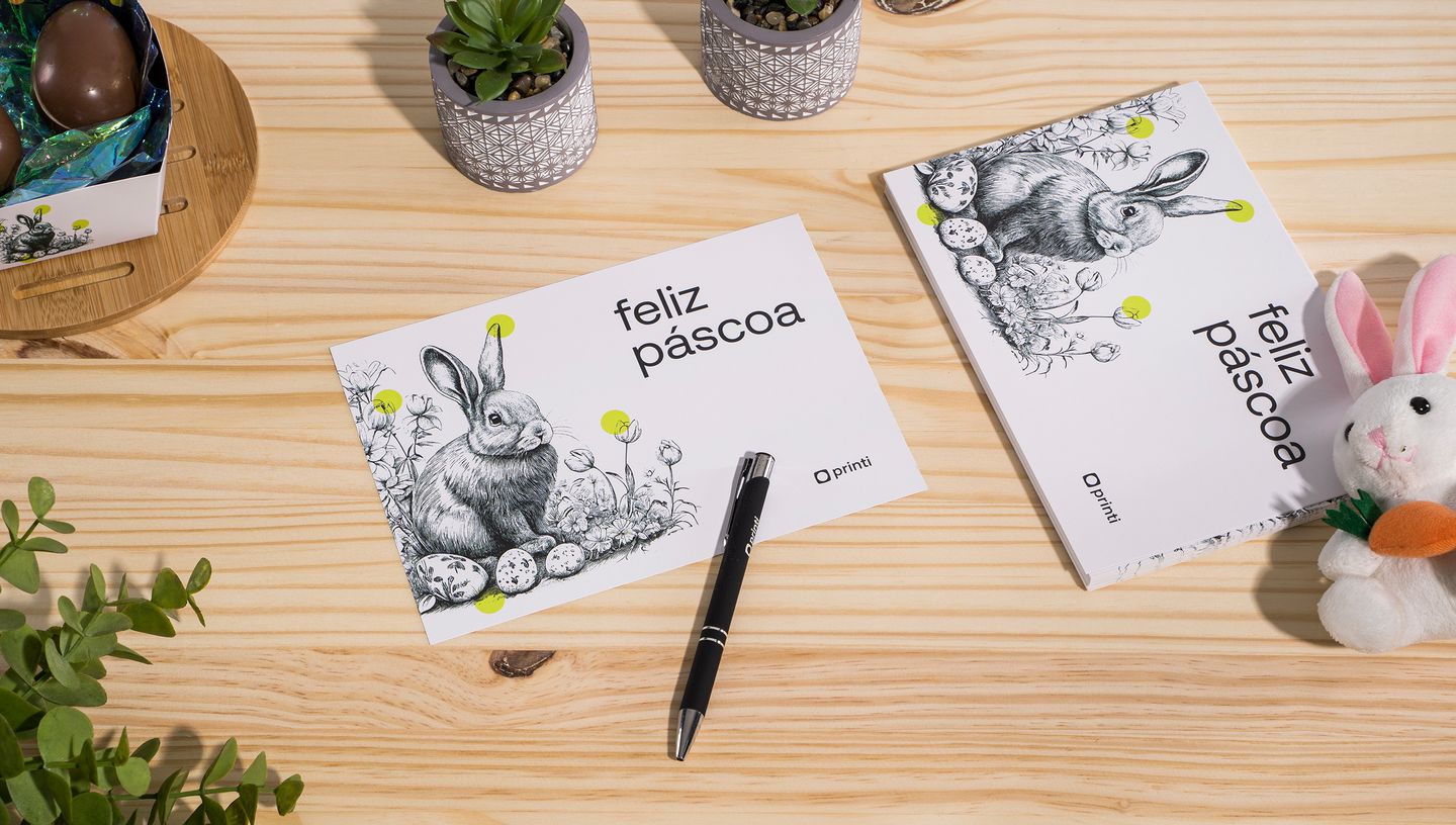 Cartão de Páscoa personalizado com ilustração de coelho e elementos de decoração temática sobre mesa de madeira.