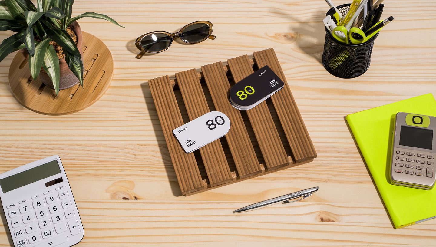 Vista superior de mesa com cartões de vale presente personalizados sobre suporte de madeira.