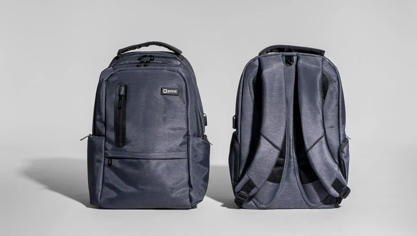 Mochila para notebook personalizada da Printi em tecido cinza, exibida pela frente e pela parte traseira, com compartimentos com zíper, alças acolchoadas e design ergonômico