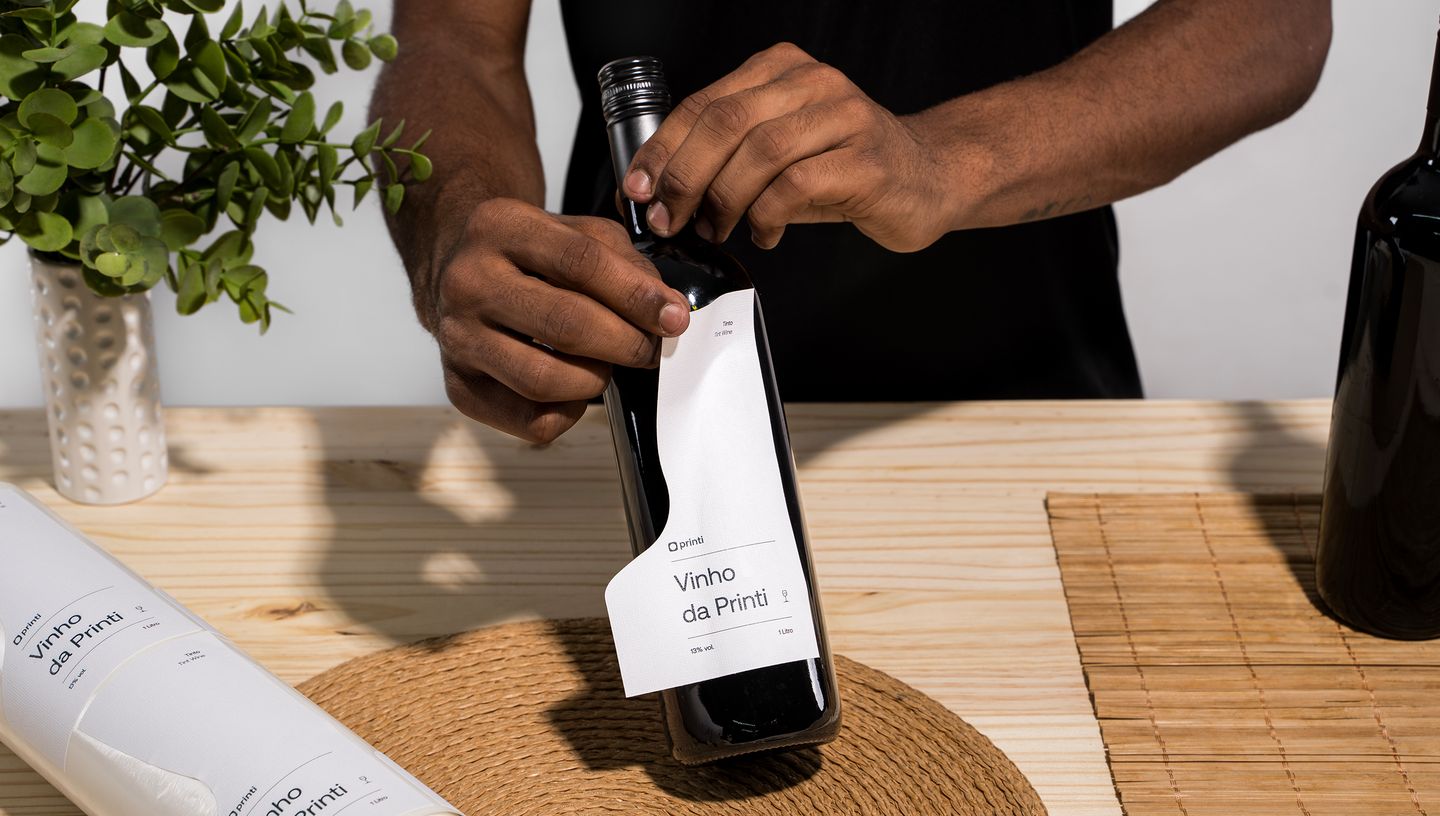 Pessoa adicionando rótulo em garrafa de vinho.
