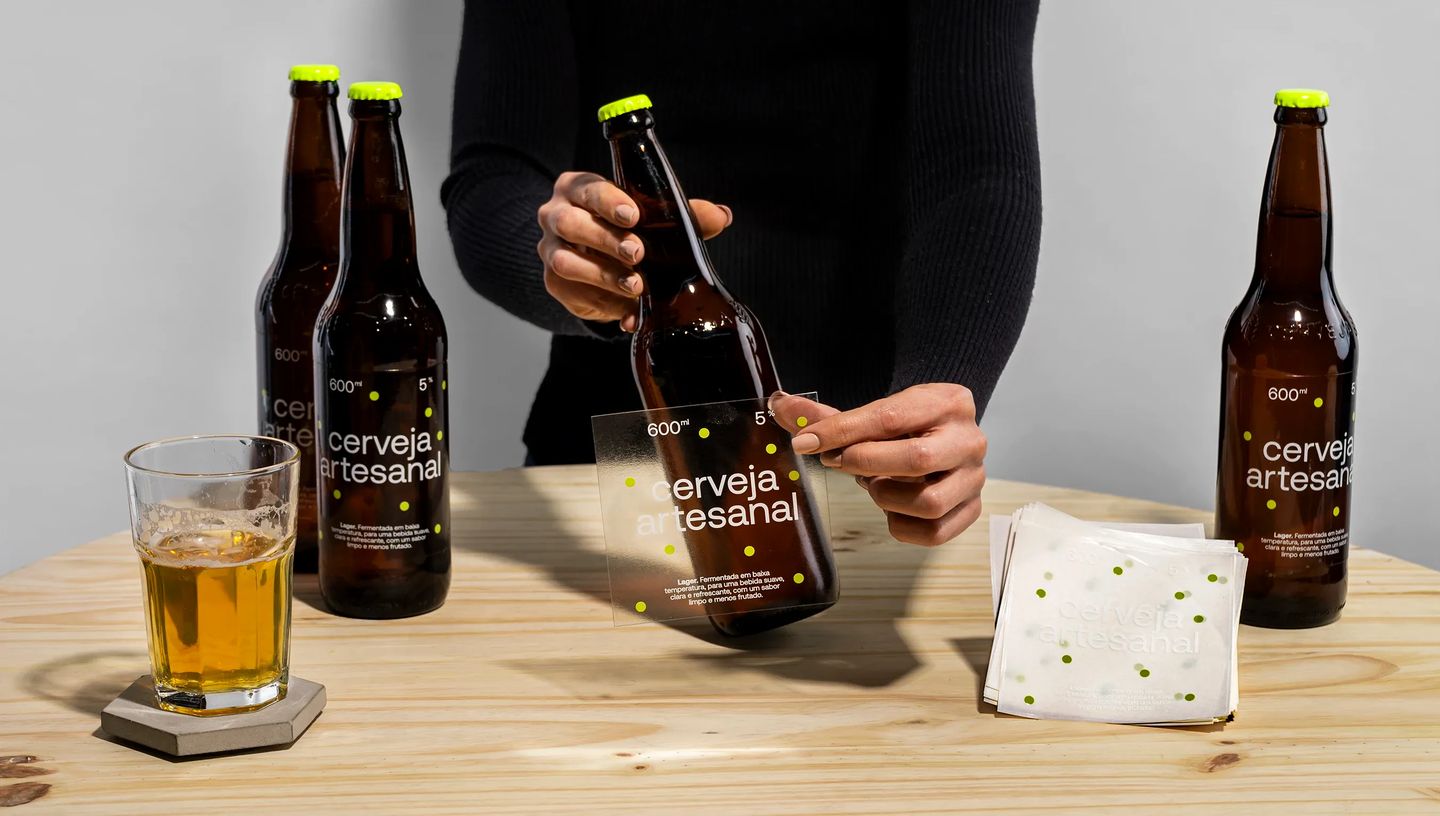 Pessoa aplicando rótulo verniz na garrafa de cerveja