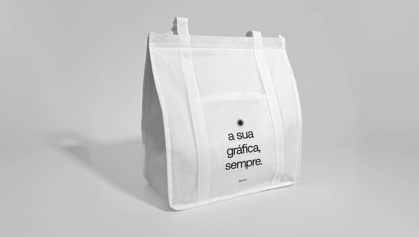 Sacola térmica personalizada em tecido non-woven branco com alças reforçadas e bolso frontal, exibindo a frase “a sua gráfica, sempre.” impressa em preto com o logo da Printi