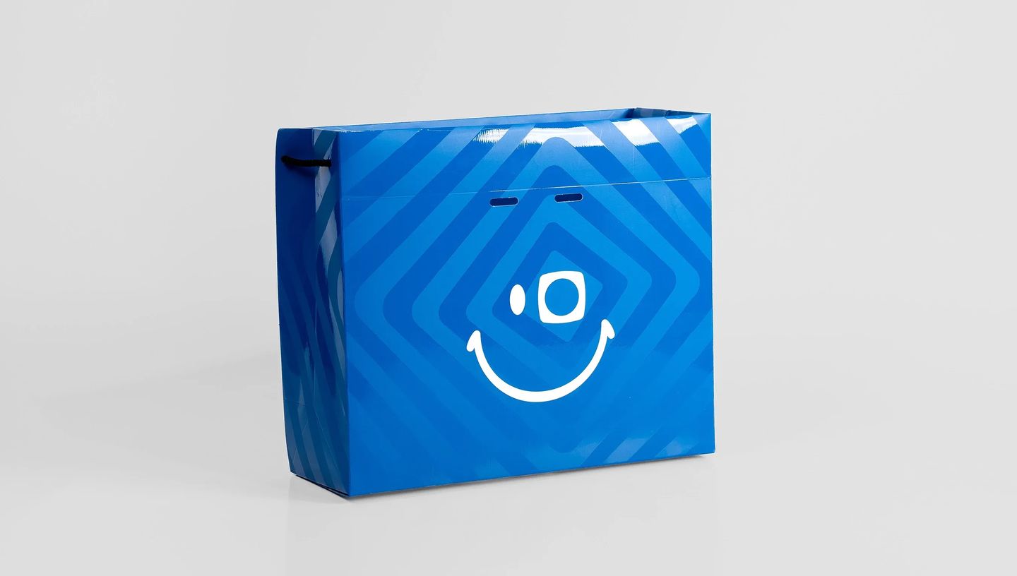 Sacola de papel azul personalizada com aplicação de verniz localizado e design de listras modernas.