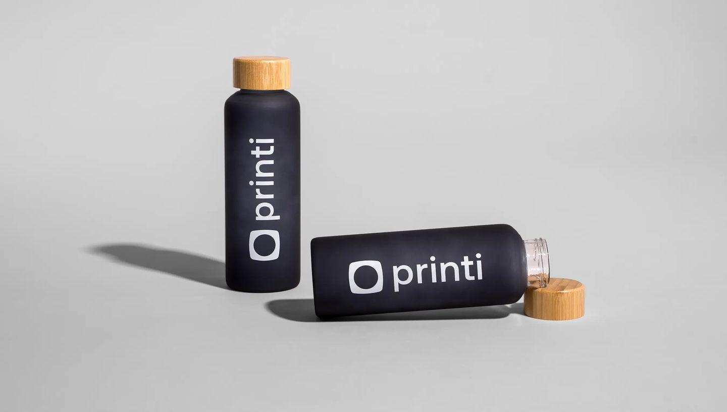 Squeeze de vidro personalizado da Printi com tampa de bambu, exibido em duas posições sobre fundo neutro