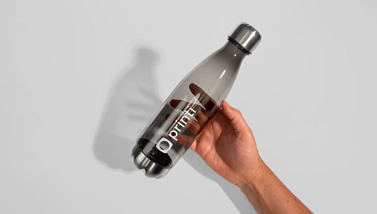 Squeeze acrílico transparente personalizado sendo segurado na mão, ideal como brinde corporativo com logotipo.