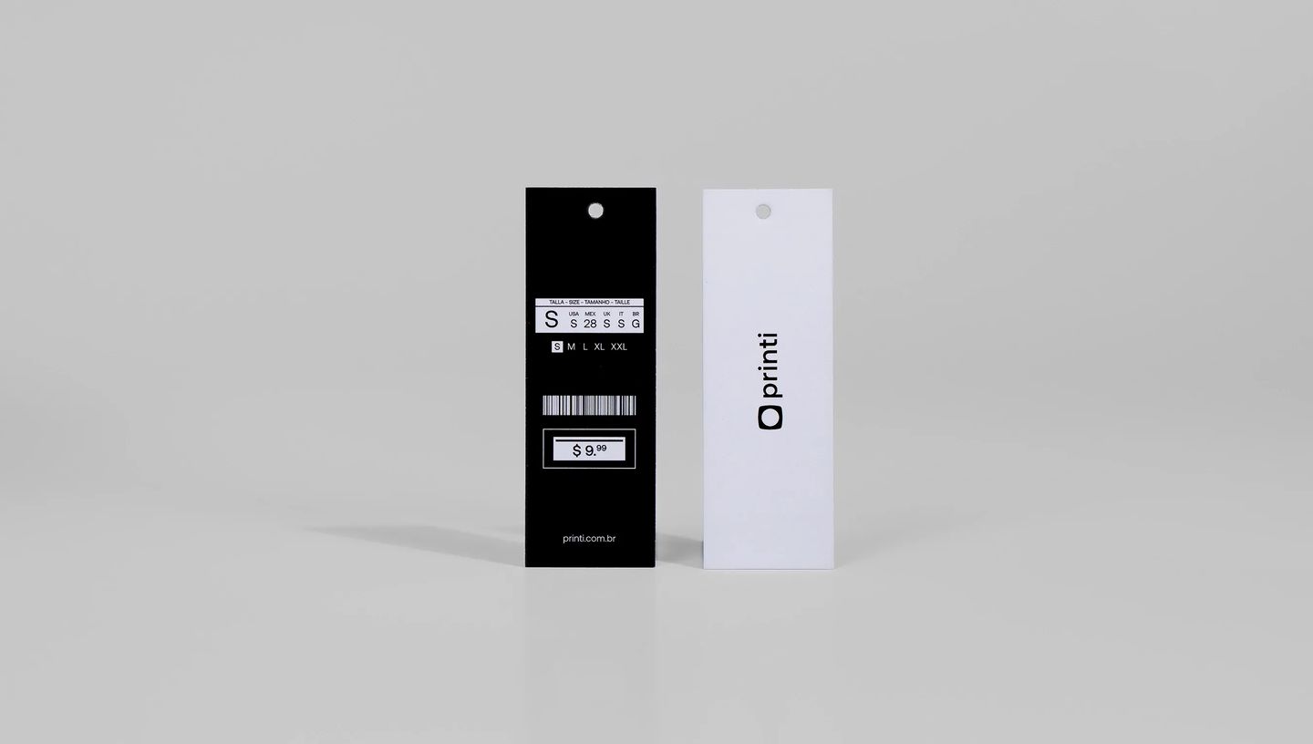 Tag para roupas personalizada da Printi em papel cartão preto e branco, com furo para fixação, contendo informações de tamanho, código de barras e preço, utilizada para identificação de peças em lojas de moda, marcas de vestuário e e-commerce.