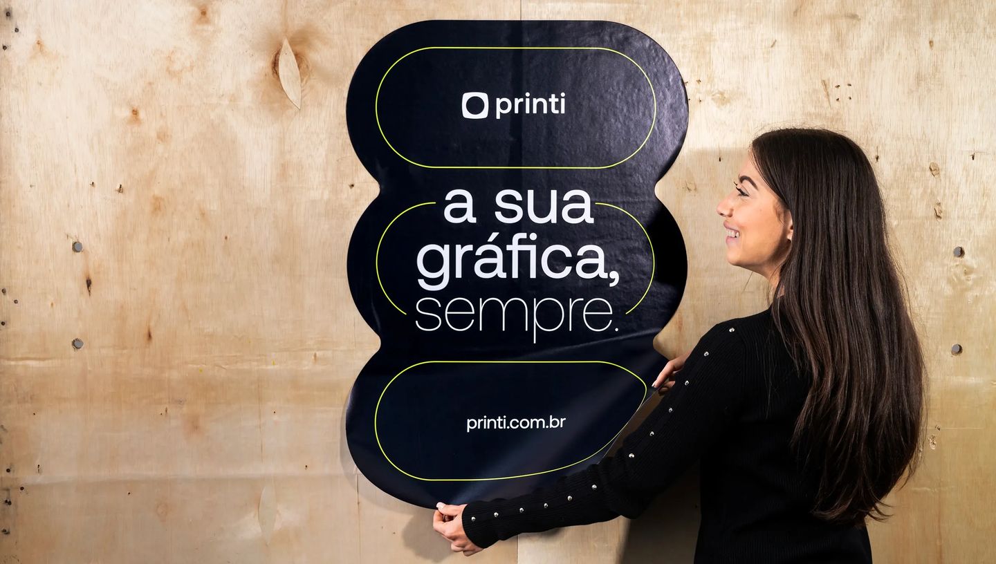 Adesivo de parede personalizado preto com frase institucional sendo aplicado em superfície de madeira.