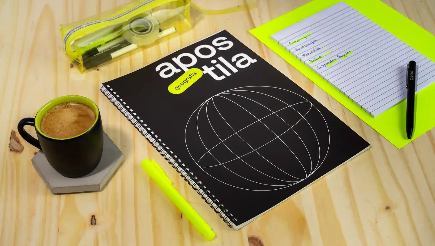Apostila com capa impressa personalizada sobre mesa de madeira, acompanhada de caderno, caneta, marca-texto e materiais de estudo.