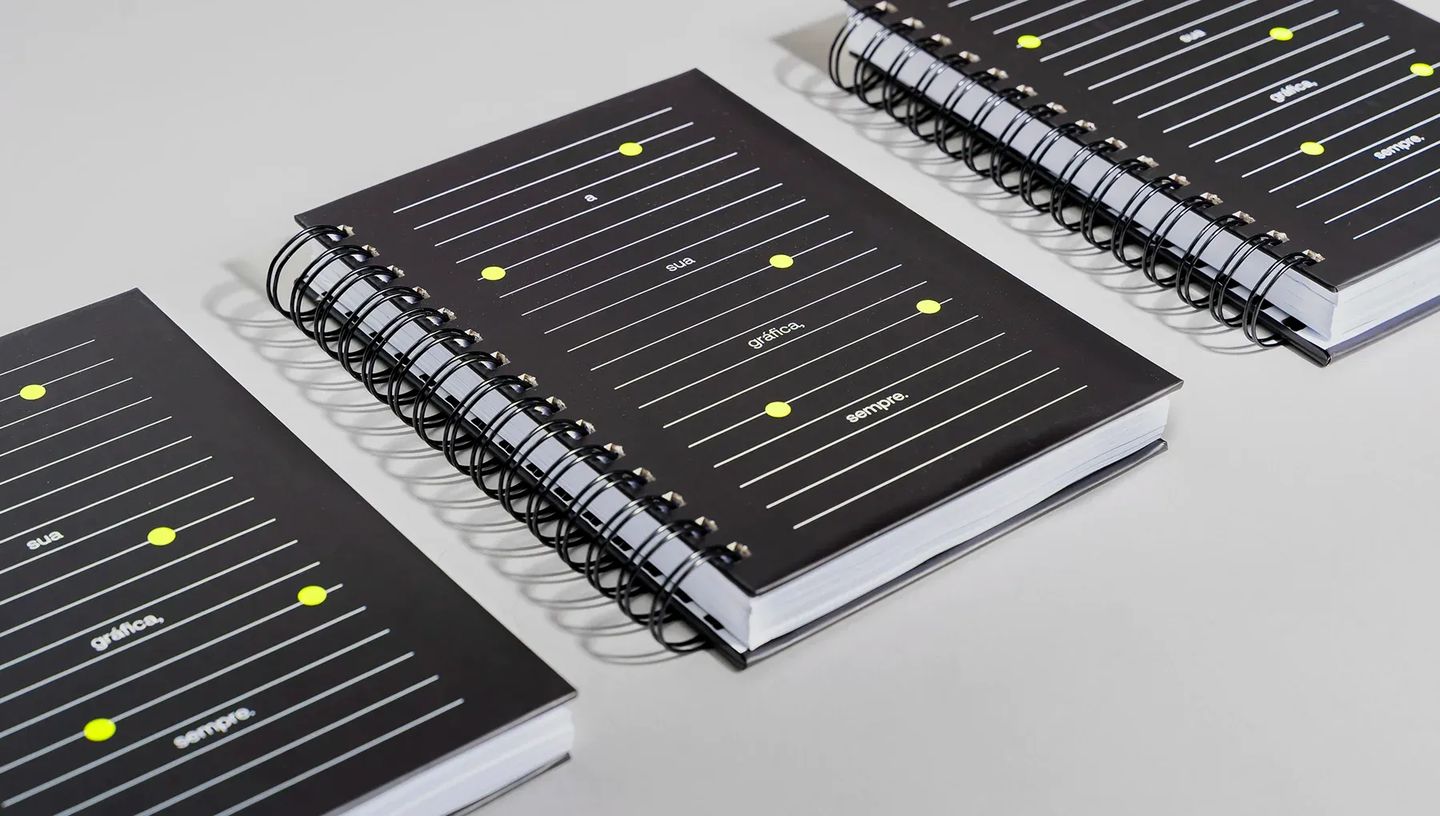 Composição de agendas permanentes da Printi em diferentes ângulos, exibindo capas coloridas, sistema de fechamento resistente.