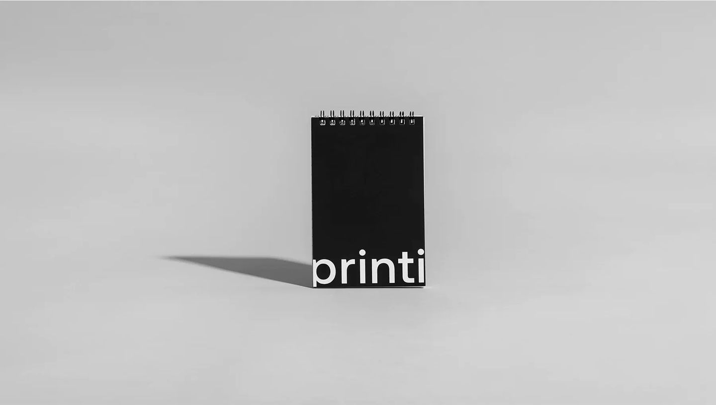 Bloco para rascunho com espiral e capa preta minimalista centralizado em fundo cinza.