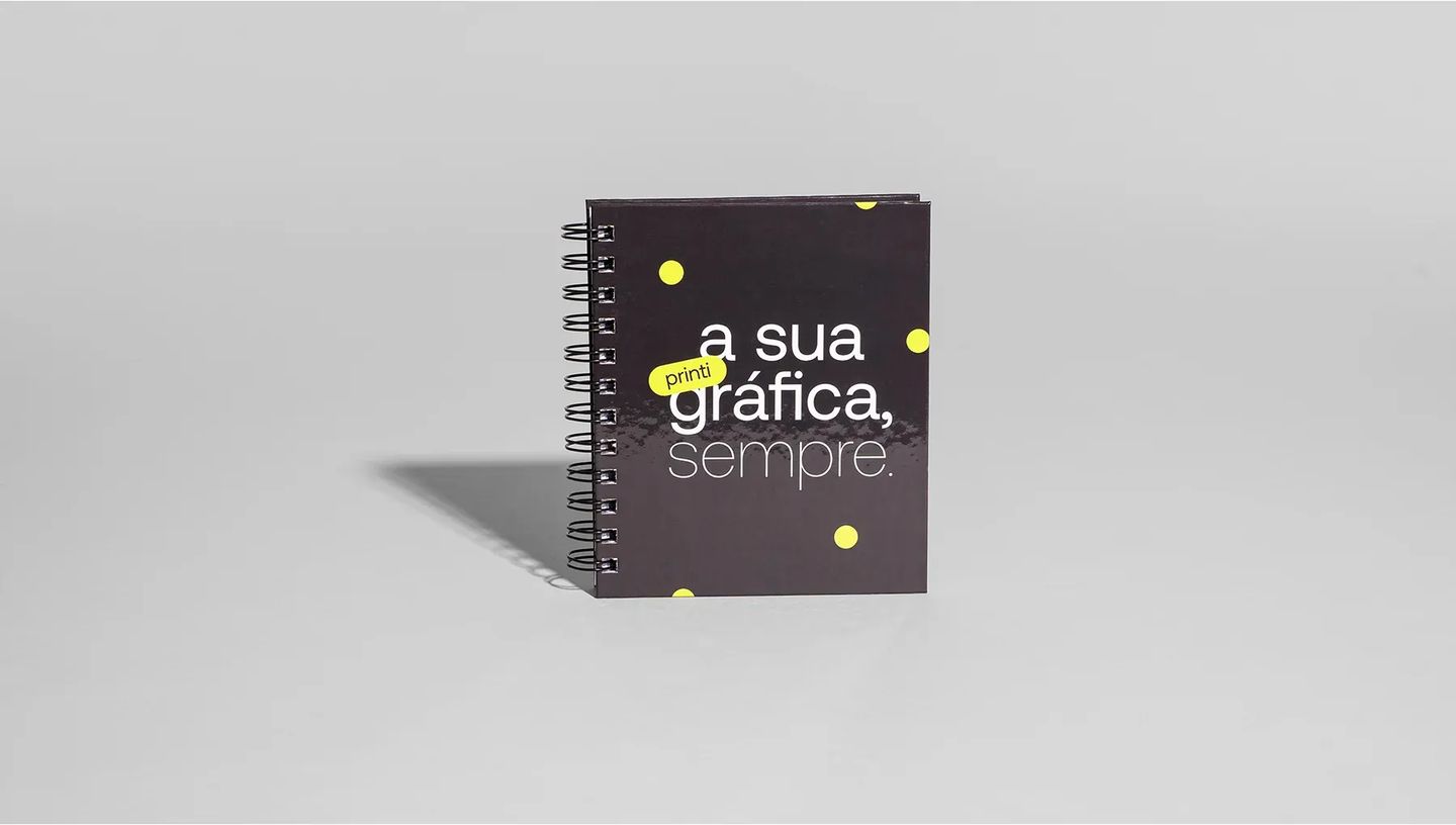 Caderno pequeno personalizado com a frase "a sua gráfica, sempre" estampada, enfatizando a nitidez da impressão e a durabilidade da capa dura para uso diário e corporativo.