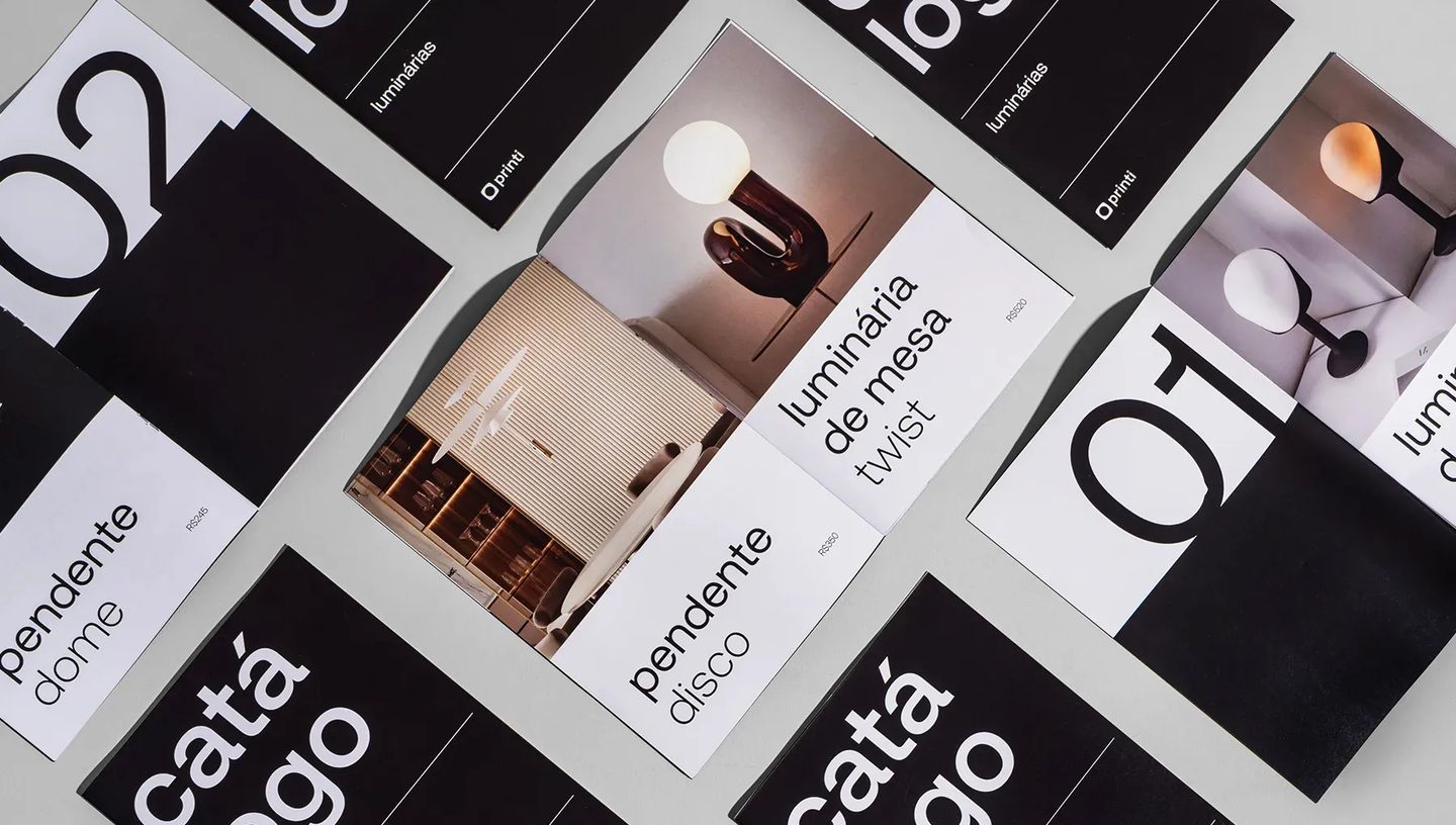 Composição de diversos catálogos impressos da Printi em preto e branco, demonstrando padronização visual e qualidade de impressão para empresas.