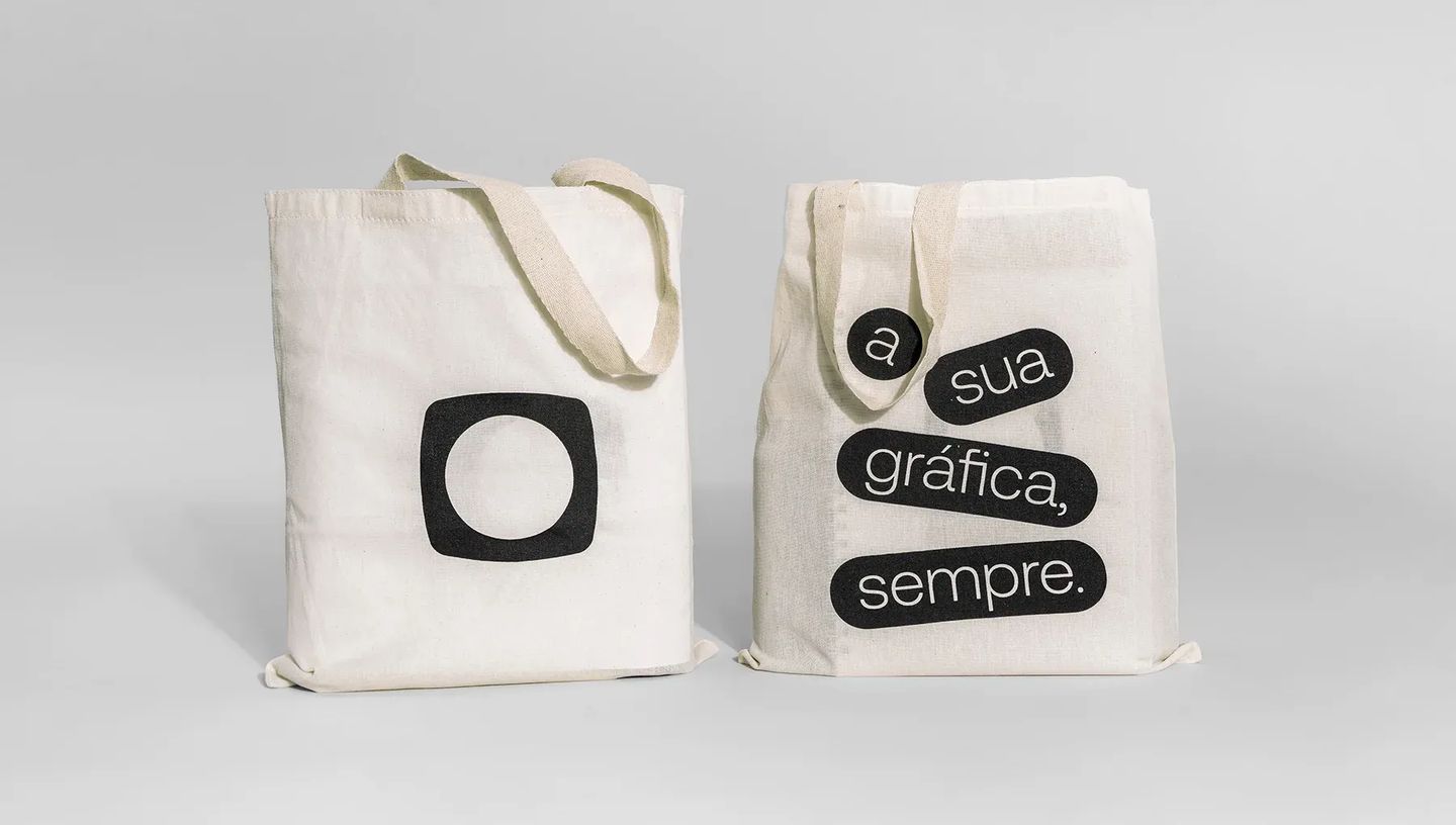 Par de ecobags de algodão cru personalizadas exibindo frente com logotipo e verso com frase institucional, ideal para eventos e ações de marketing.