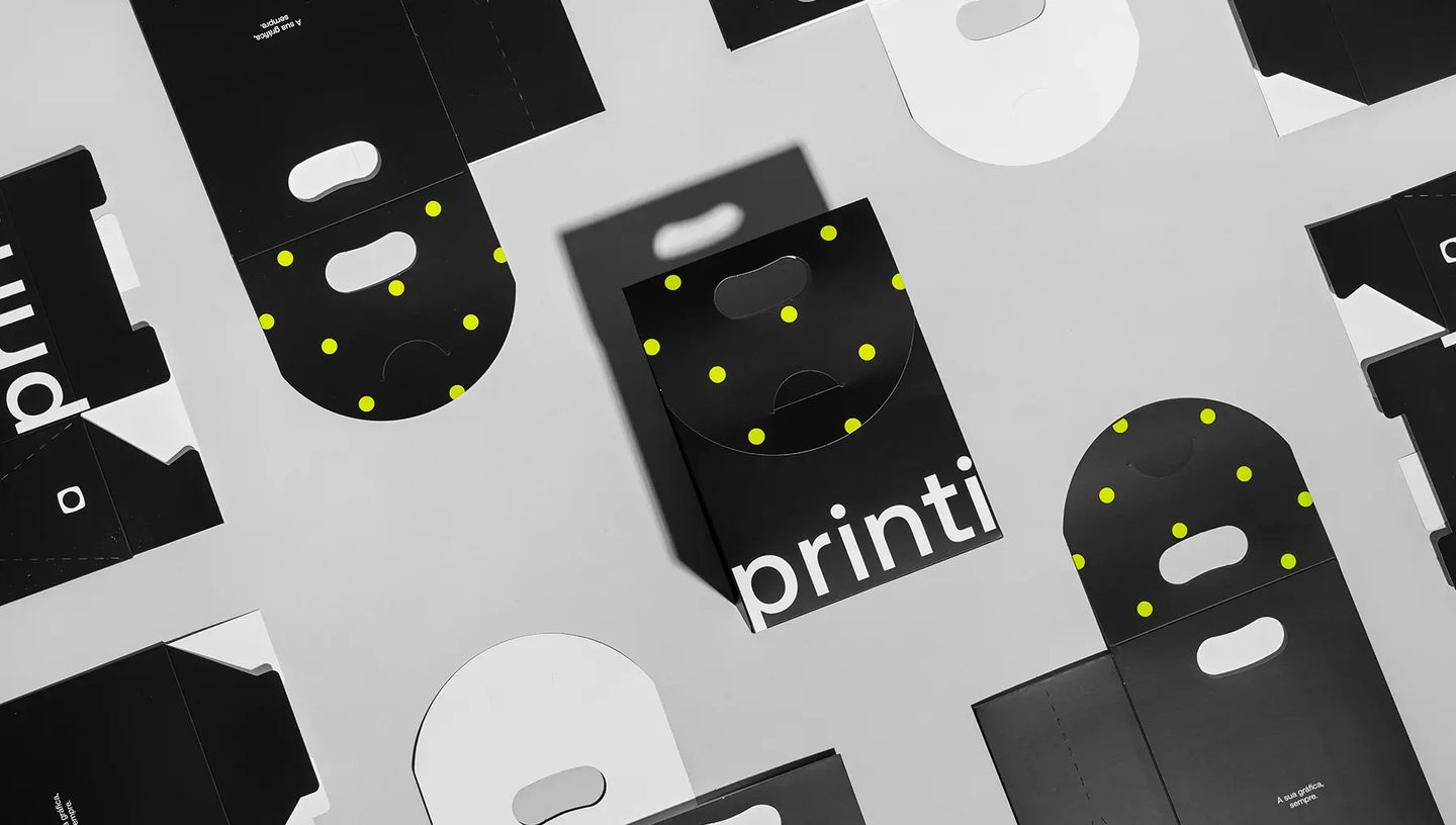 Composição de diversas embalagens sacola personalizadas da Printi em preto com poás amarelos, exibindo o produto aberto e fechado sobre fundo cinza.