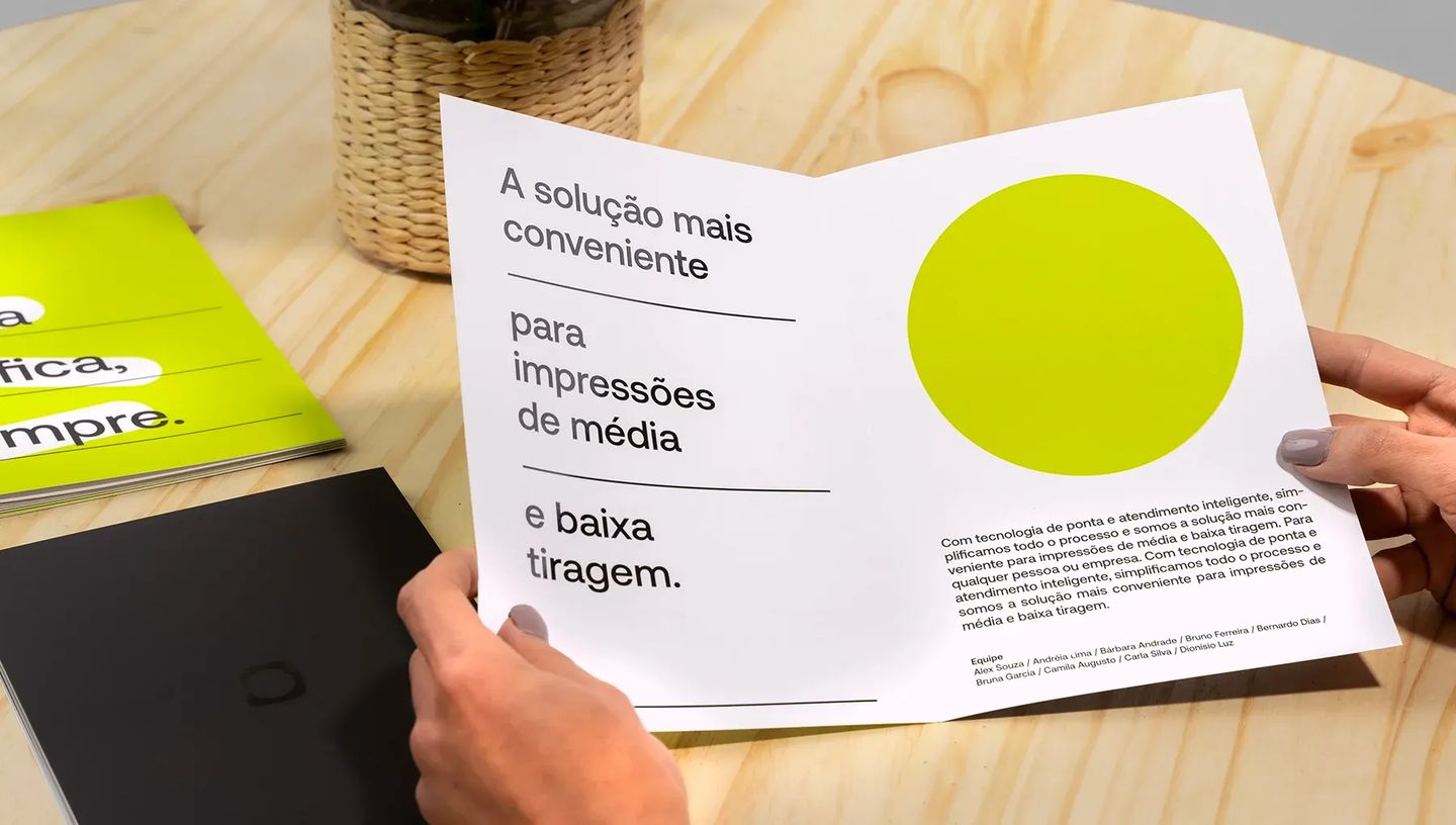 Mãos segurando folder personalizado com 1 dobra aberto, destacando a frase "A solução mais conveniente para impressões de média e baixa tiragem".