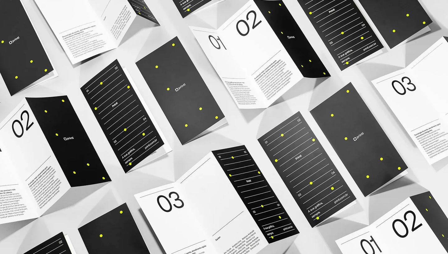 Padrão de folders impressos com 2 dobras da Printi espalhados, demonstrando qualidade gráfica e acabamento profissional.
