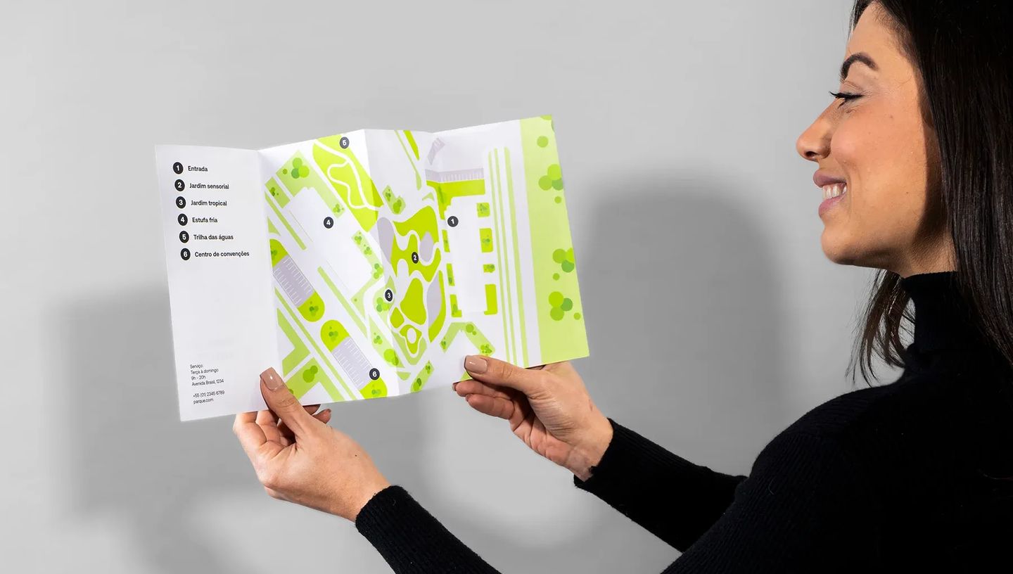 Mulher segurando folder personalizado com 3 dobras aberto, exibindo layout interno com mapa e informações detalhadas de serviço.