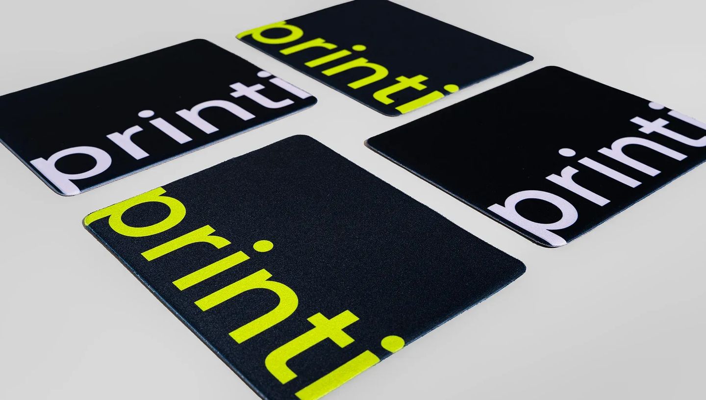 Detalhe de mouse pad personalizado retangular com a frase "A sua gráfica, sempre" em preto e amarelo sobre fundo cinza.