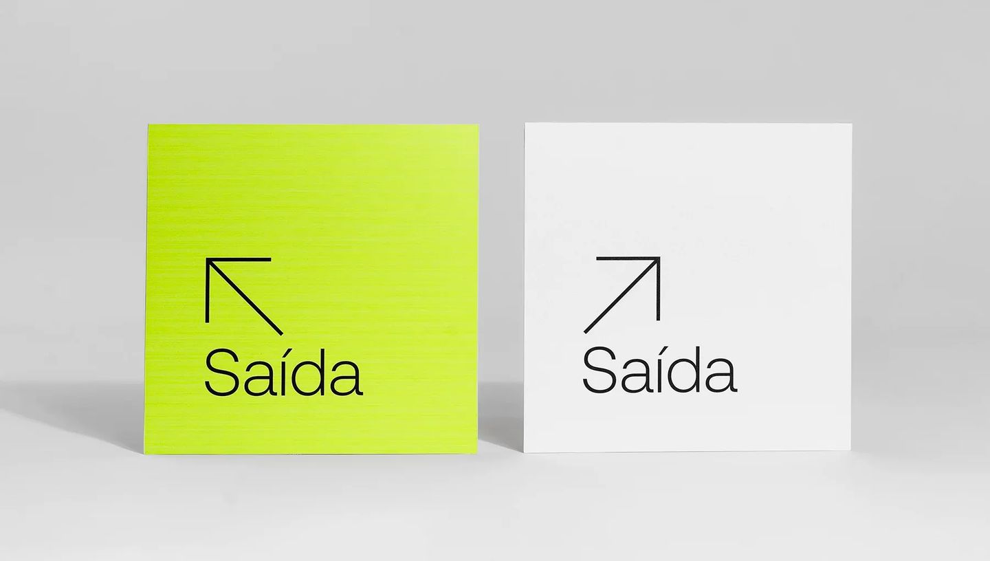 Par de placas de sinalização de saída personalizadas em verde neon e branco, com design minimalista e seta indicativa para comunicação visual interna.